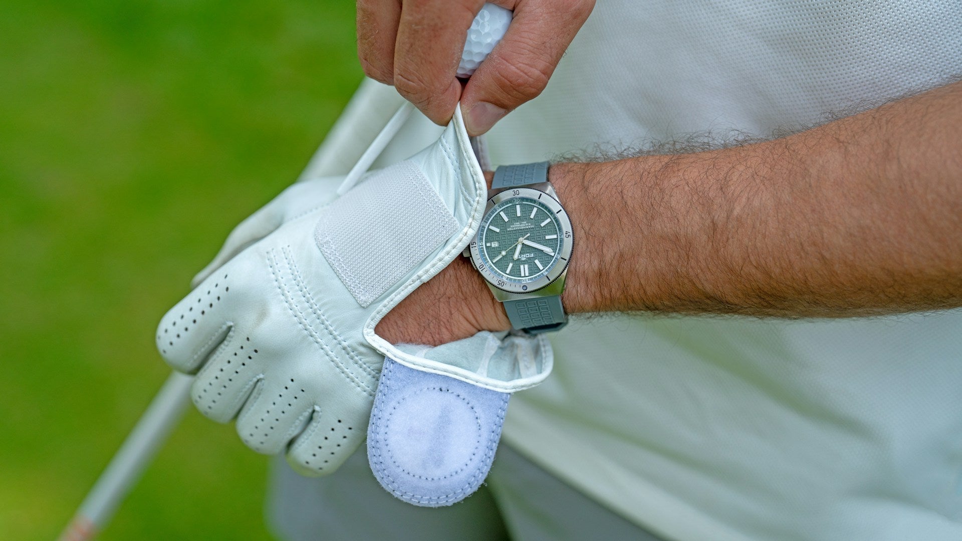 detail of a golf player putting on a golf glove about to choose between a interlocking or a overlap grip for his next shot