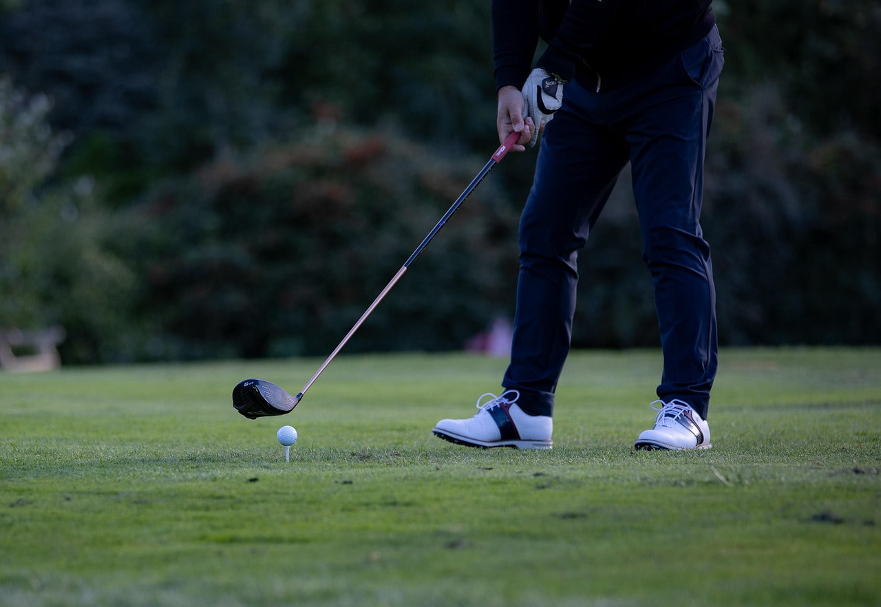 detail of the golf shoes of a golf player playing in a course at dusk
