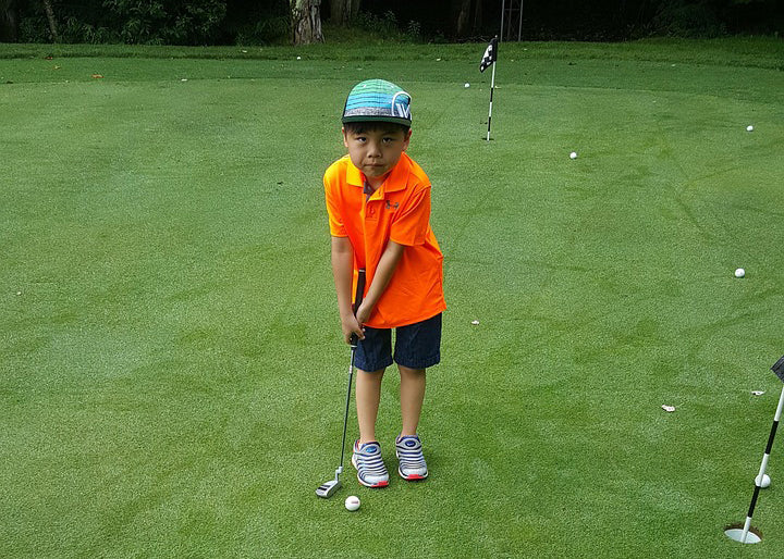 junior golf player about to put in a golf field looking at the camera