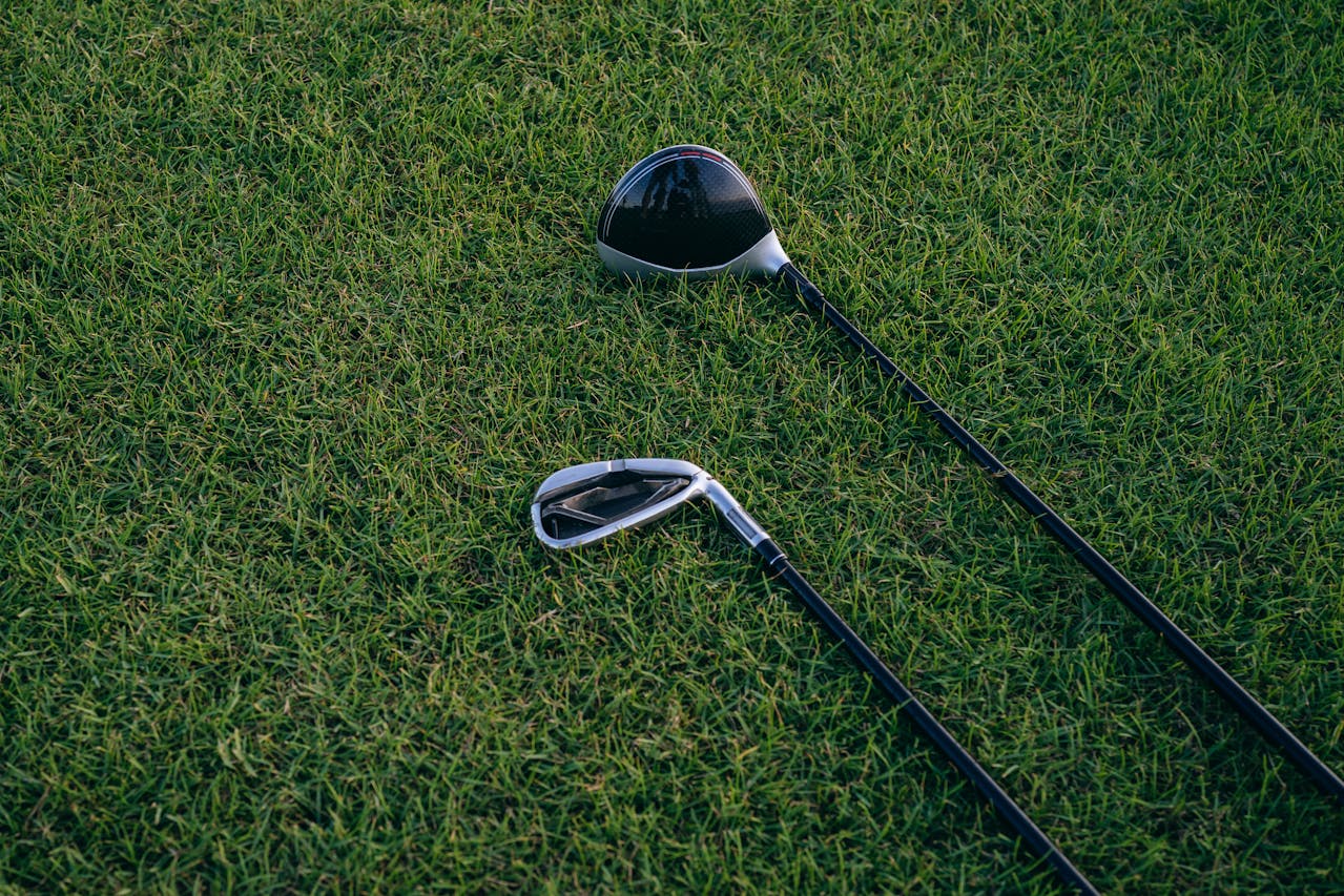 golf driver and iron laying in the grass of a golf field