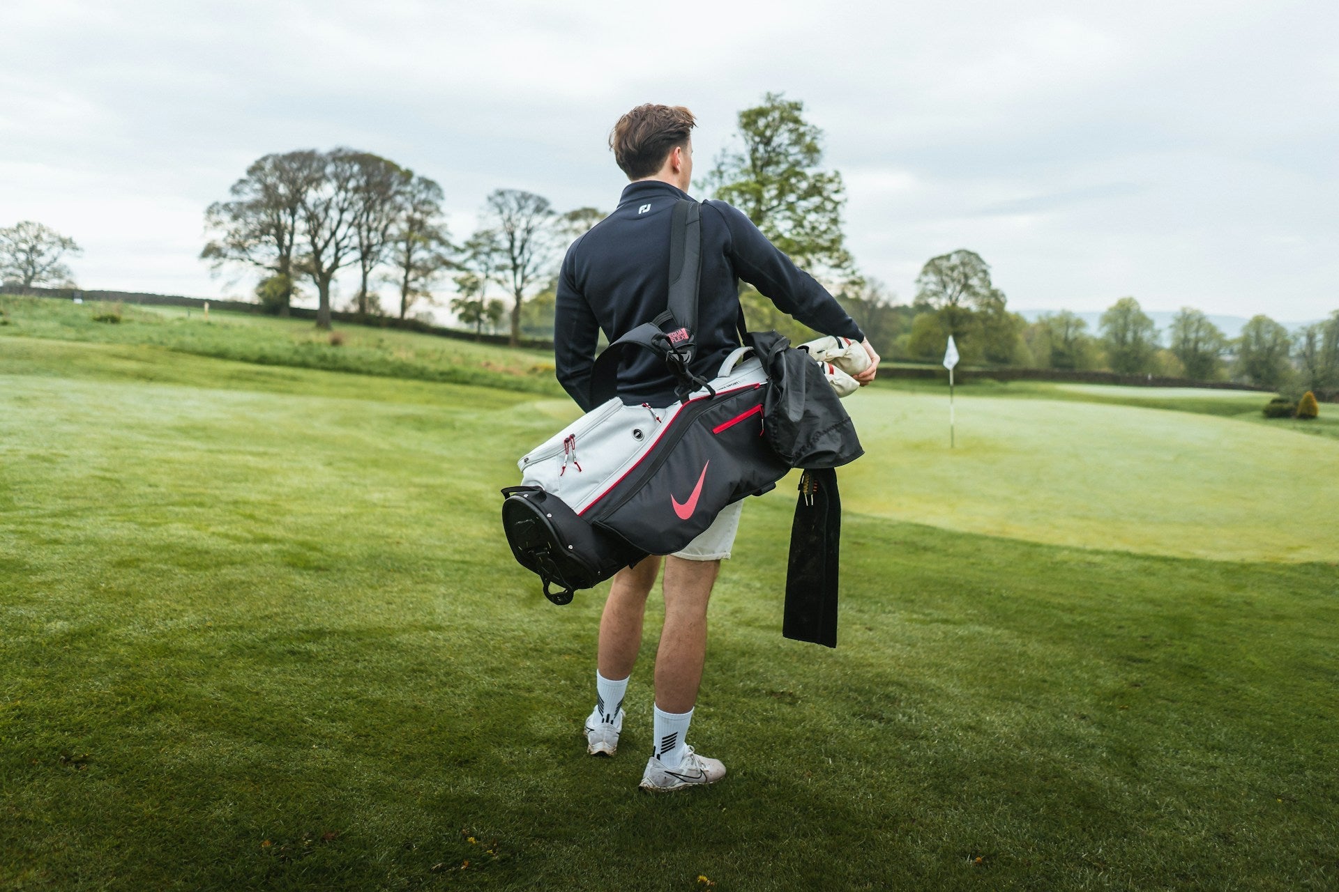 player carrying golf bag in a golf field