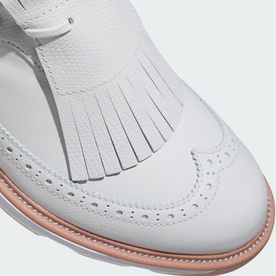 Close-up of the Adidas MC Zoysia Ladies Spikeless Golf Shoes in grey, featuring a white leather upper, tan sole, and decorative fringe on top—blending classic brogue style with modern comfort for women golfers.