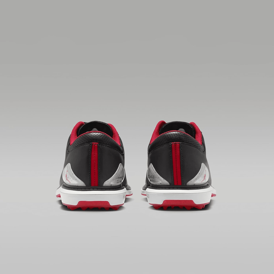 A pair of Jordan ADG 5 Golf Shoes - Black, featuring black, red, and white colors, is shown from the back against a gray gradient background.