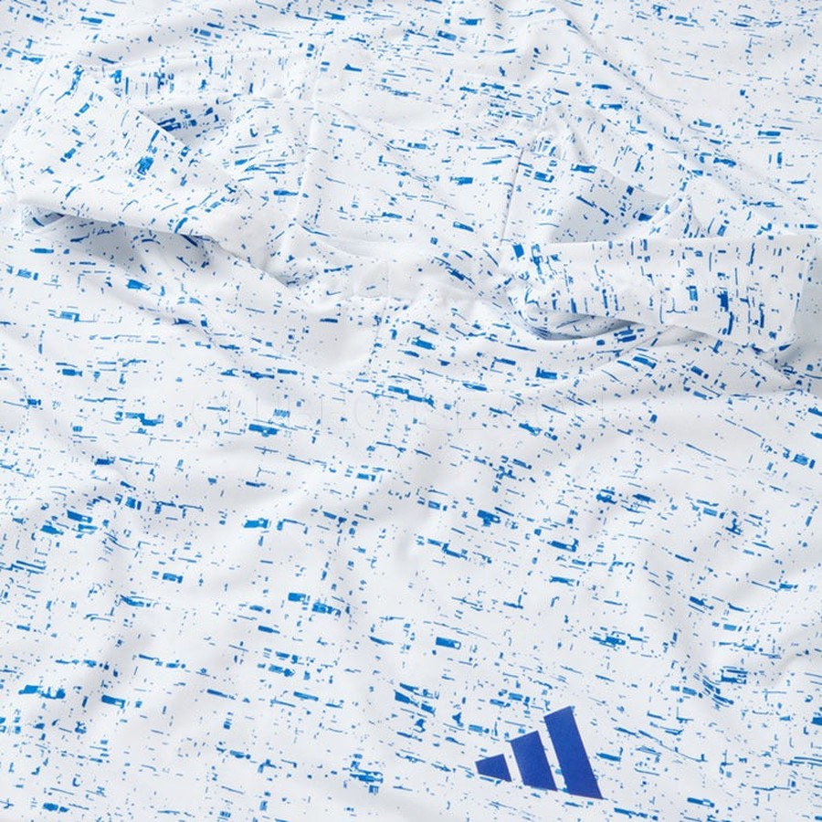 A close-up of white stretchy fabric from the Two Pack Adidas Core Printed Lightweight Hoodies, featuring an abstract blue speckled pattern and a blue Adidas Core logo in the lower right corner.