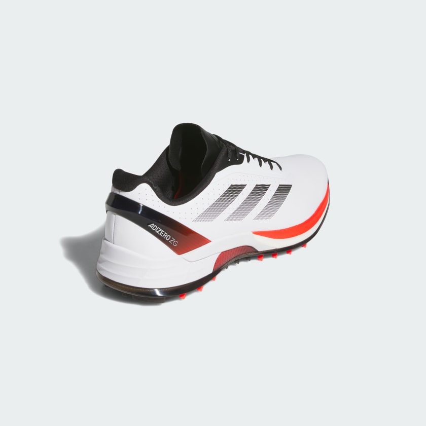 The Adidas Adizero ZG Spikeless Golf Shoes in White/Red have black and red accents, black laces, three black stripes, and a waterproof upper. They are shown from the back and side on a light background.