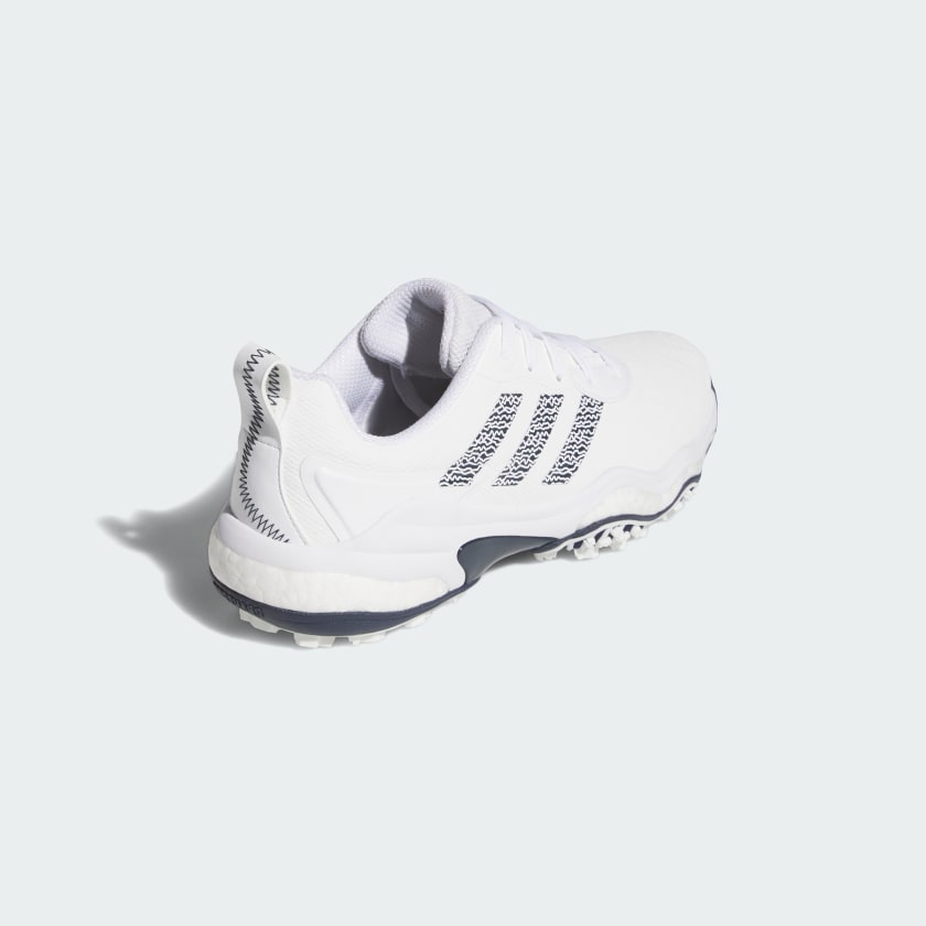 The Adidas Codechaos 25 Spikeless Golf Shoes in White/Navy, featuring a textured sole and crafted from recycled materials, are displayed from a rear-side angle on a light background.