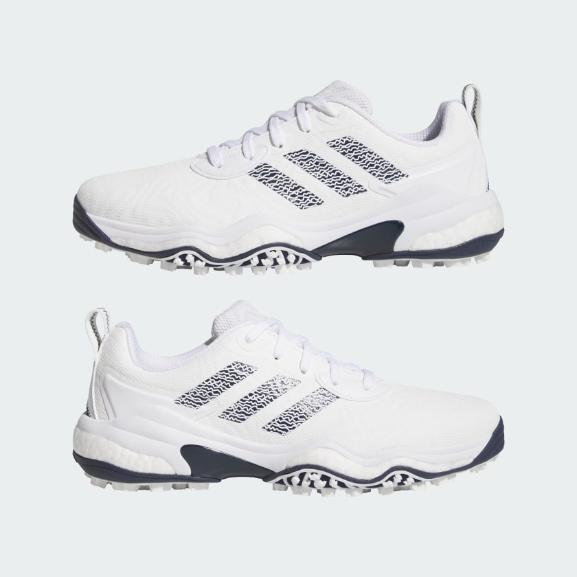 The Adidas Codechaos 25 Spikeless Golf Shoes in White/Navy feature textured soles and a modern look, with navy accents and three stripes on the sides. A side view shows off their sleek, contemporary style against a light background.