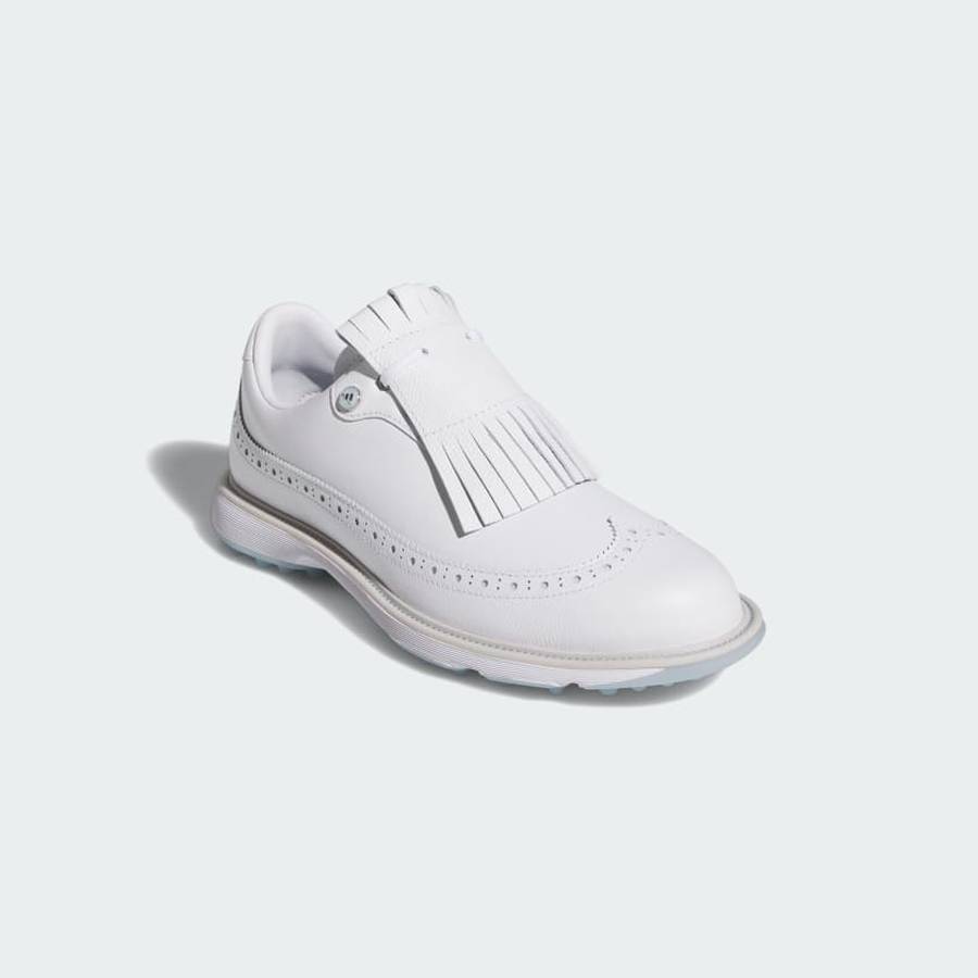 The Adidas MC Zoysia Ladies Spikeless Golf Shoes in white feature decorative perforations and a removable fringe kiltie over the laces, displayed on a plain light background.