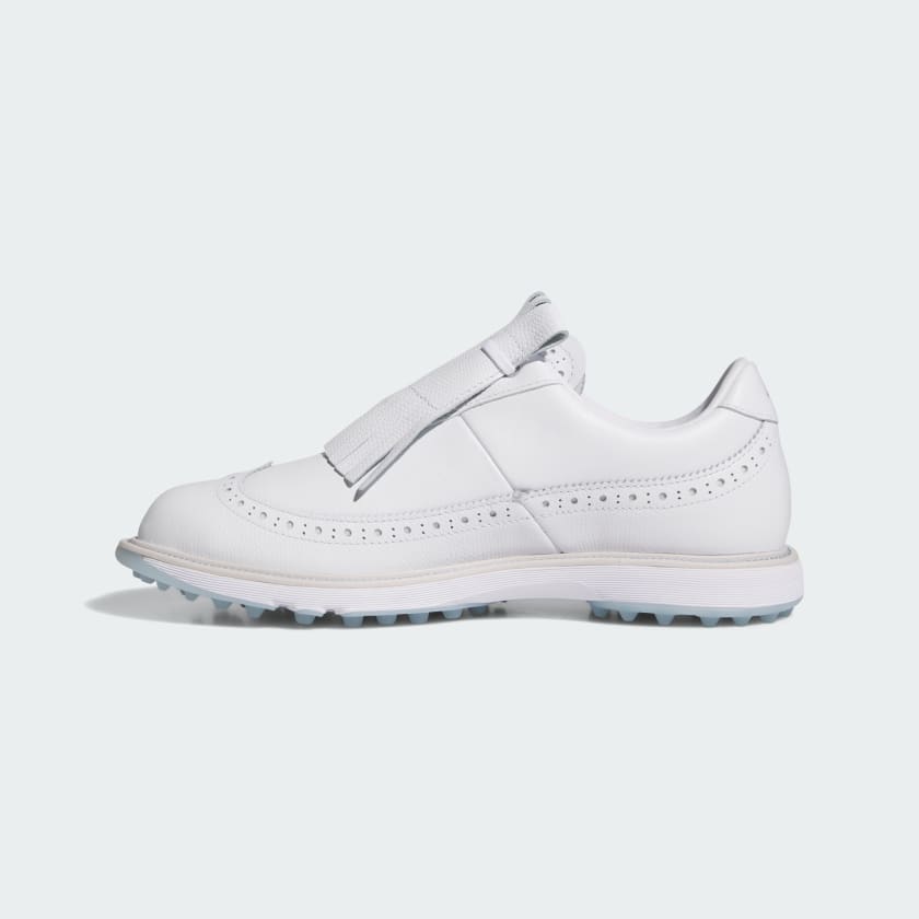 The Adidas MC Zoysia Ladies Spikeless Golf Shoes in white feature brogue detailing, perforated accents, a fringe kiltie overlay with strap, and BOOST comfort. Shown in a side profile view against a light background.