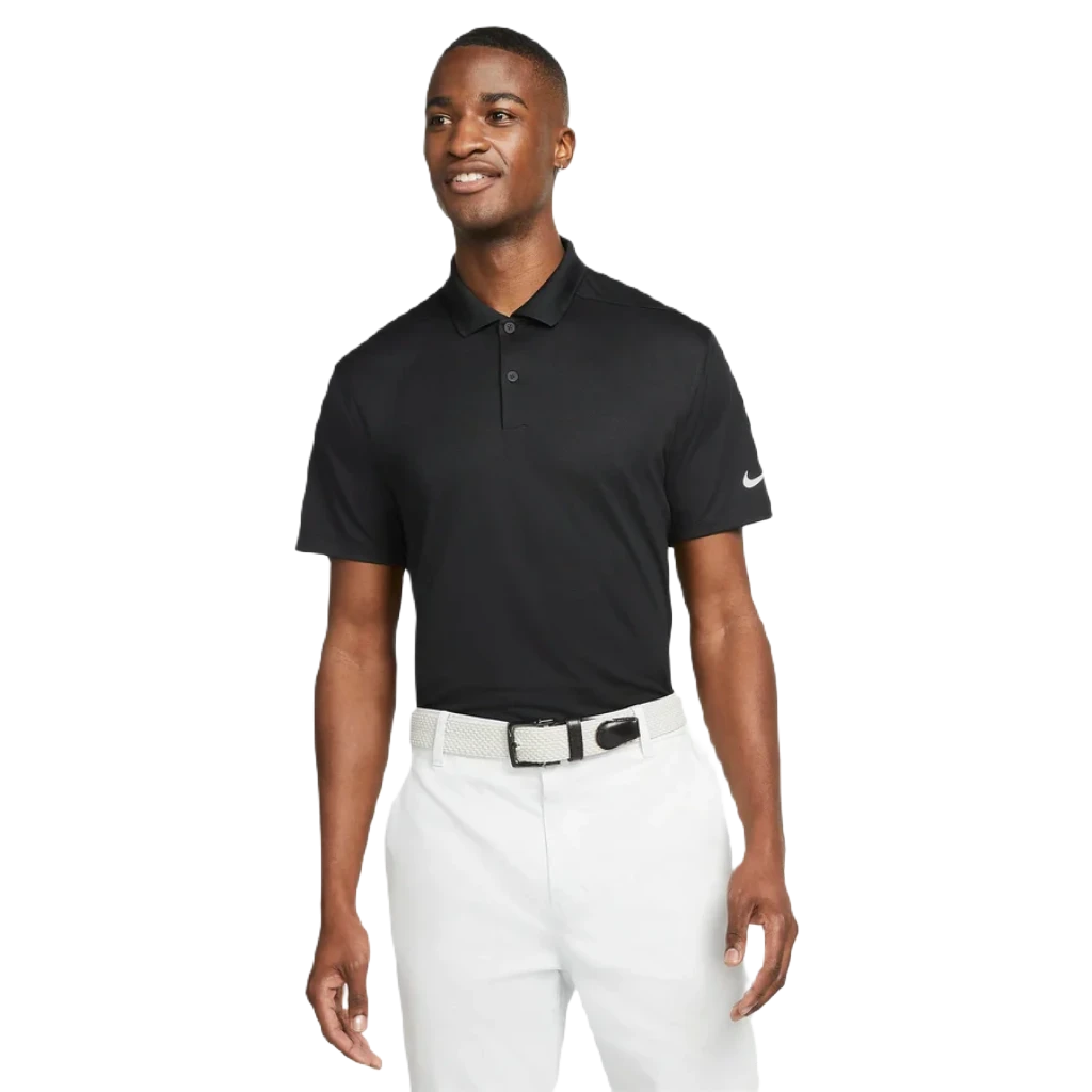 A man smiles in the Nike Dri-FIT Victory Men's Golf Shirt - Course/Event Logo (Final Sale), styled with white pants and a woven belt, showcasing its classic look against a plain white background.