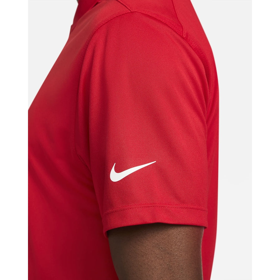 A person wearing a red Nike Dri-FIT Victory Men's Golf Shirt with short sleeves and a white swoosh logo on the left sleeve.