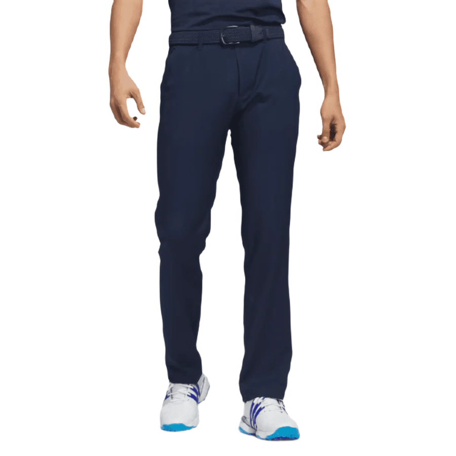 A person wearing Adidas Ultimate365 Pants - Blue with UV protection, a matching belt, and white sneakers with blue and purple accents, shown from the waist down on a white background.