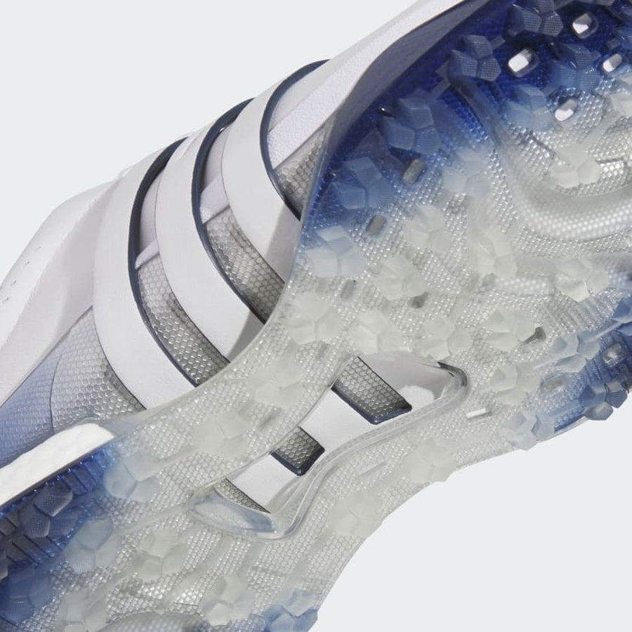 Close-up of the translucent, textured 3D Traxion outsole on the Adidas Tour360 25 Spikeless Golf Shoes in grey, showing hexagonal grip patterns for superior traction and a white and navy-blue upper with gradient edges.