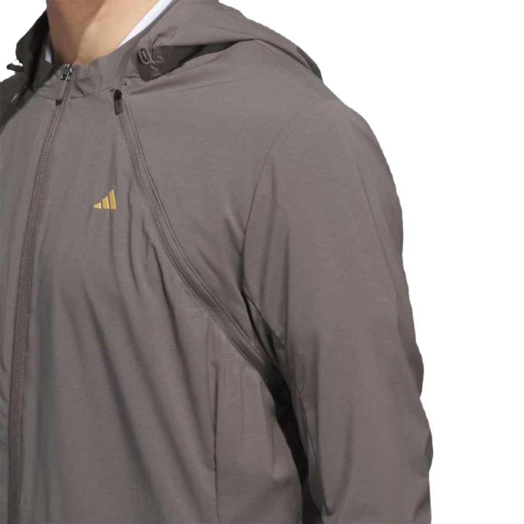 A person wearing the Adidas Ultimate365 WIND.RDY Convertible Jacket in brown with a small yellow logo on the chest, shown from the shoulders down against a white background.