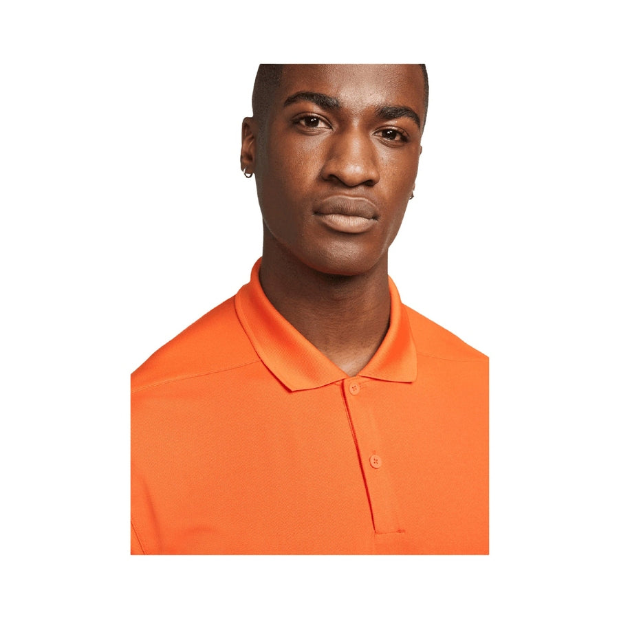 A person in a bright orange Nike Dri-FIT Victory Men's Golf Shirt with Course/Event Logo looks at the camera, showing only their face and upper torso against a white background, highlighting the shirt's sleek design. Final Sale.