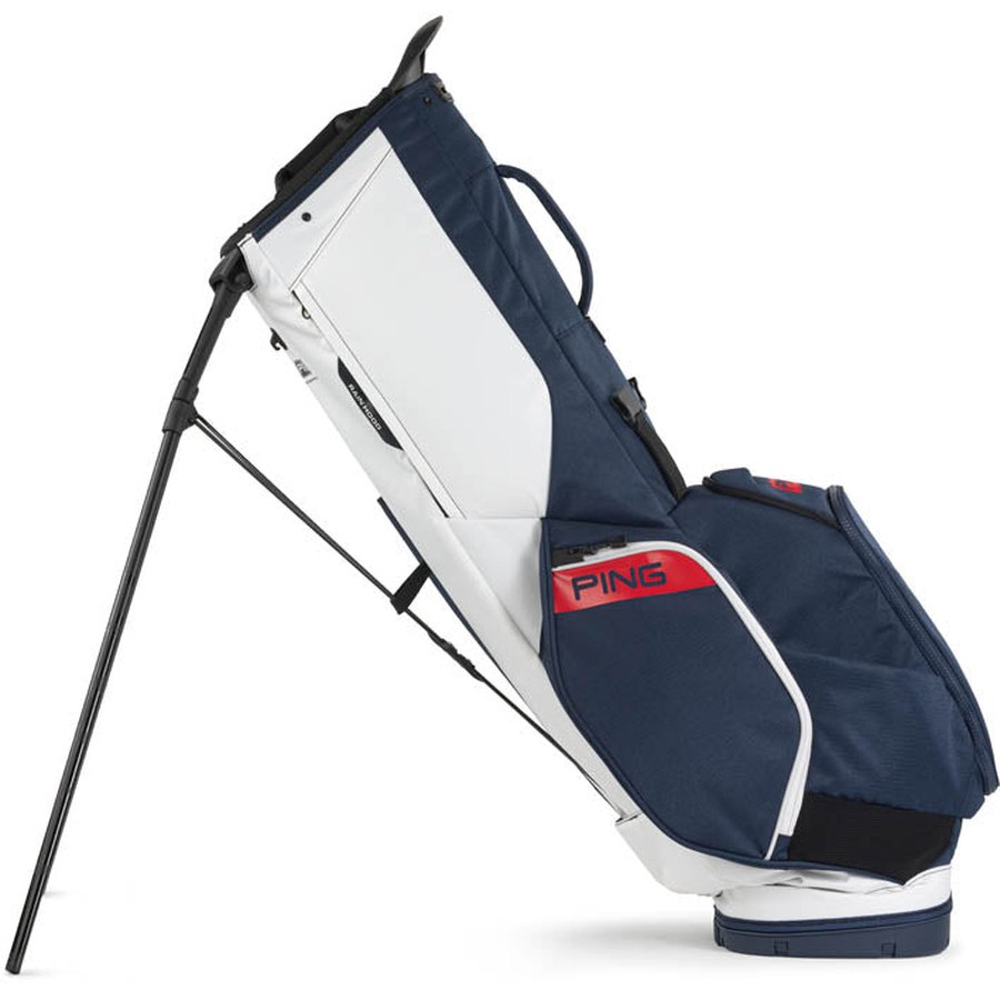 The Ping Hoofer 231 Golf Carry Bag is a lightweight blue and white model with black legs extended, standing upright on its stand and displaying a red Ping logo on the side pocket.
