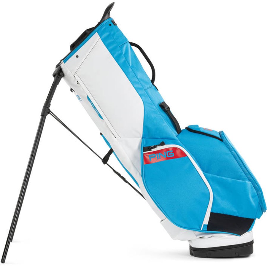 The Ping Hoofer 231 Golf Carry Bag is a lightweight blue and white bag with black legs extended, a red PING logo on the side pocket, 16 pockets, multiple compartments, and a top handle for easy carrying.