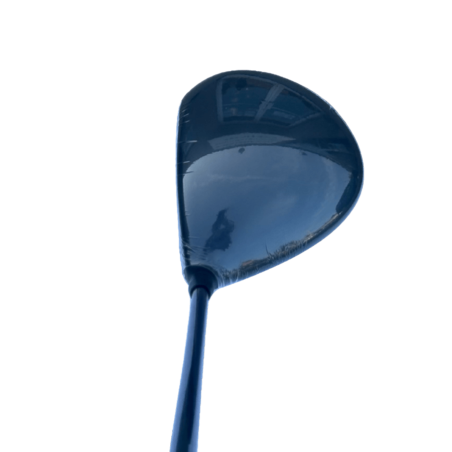 A close-up of the Cobra Darkspeed Tour Issue Long Drive LS Driver with HZDRUS Green Shaft shows the head angled upward, its shiny surface reflecting the sky and a building, set against a plain white background.