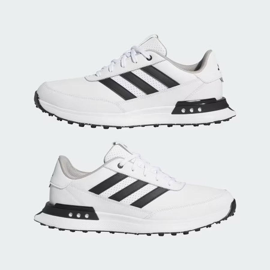 The Adidas S2G 24 Leather Spikeless Golf Shoes in White/Black are shown from the side against a light gray background, featuring black stripes and soles. Both spikeless shoes face right, displaying their outer sides.