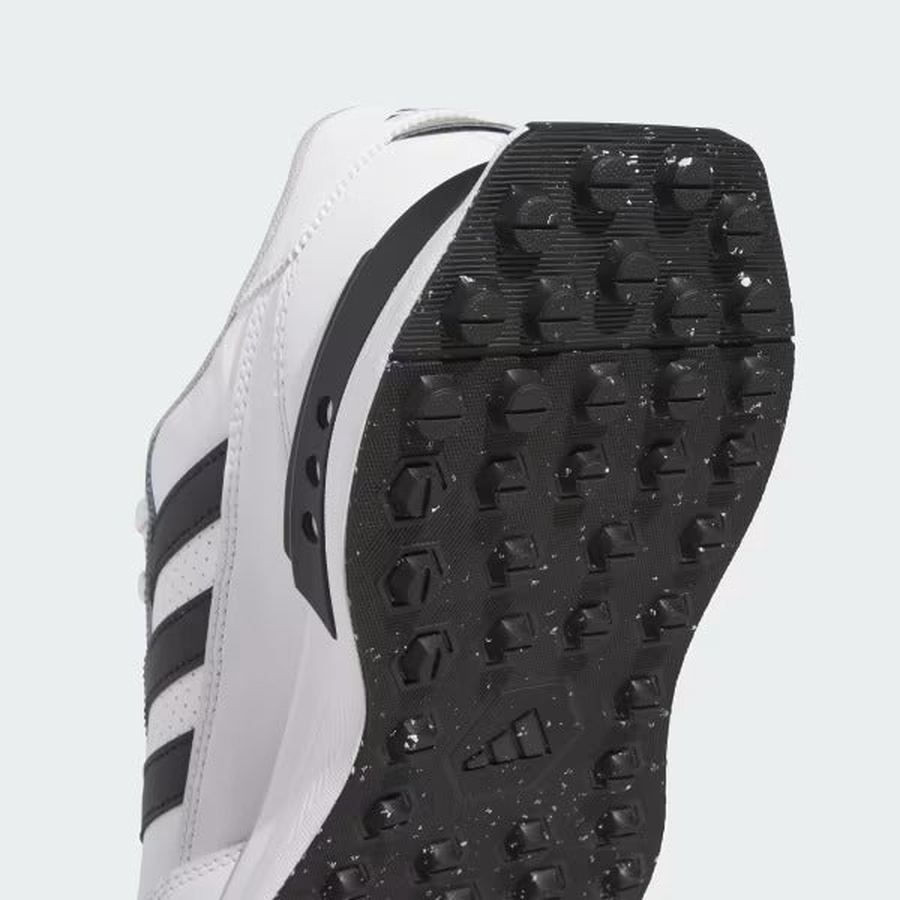 Close-up of the sole of the Adidas S2G 24 Leather Spikeless Golf Shoes in White/Black, showing black grip-patterned rubber outsole with white speckles and classic black stripes on a running-inspired design.