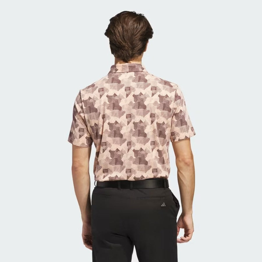 A man is seen from behind wearing the Adidas 2025 Go-To Printed Polo Shirt in pink and brown, made with recycled materials, tucked into black pants, standing against a plain light gray background.