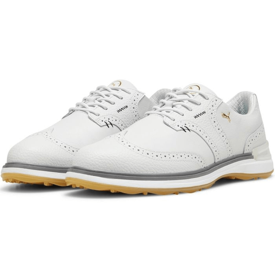 The PUMA Avant Wingtip Golf Shoes - Grey feature white leather, gray detailing, perforated accents, light brown rubber soles, and white laces. These spikeless golf shoes combine sporty comfort with classic style for casual or athletic wear.