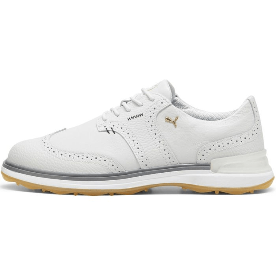 The PUMA Avant Wingtip Golf Shoes - Grey feature a white leather upper with perforations, light gray midsole, tan rubber outsole, and a gold side logo—delivering spikeless comfort and timeless style for both on and off the course.