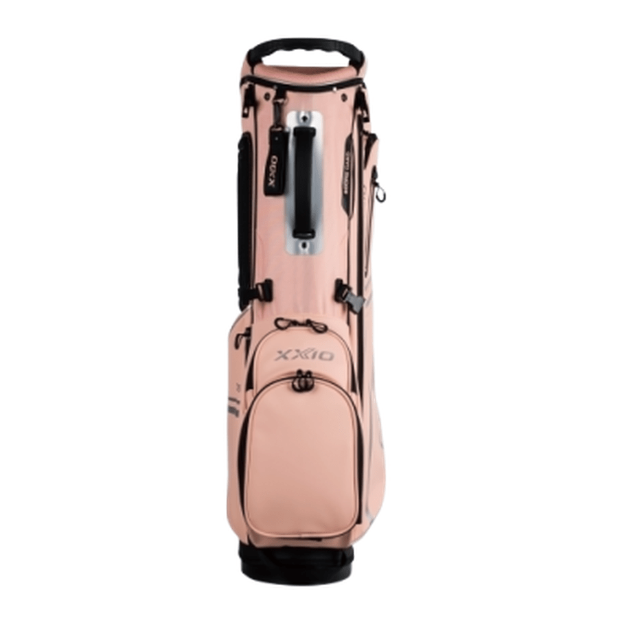 The XXIO Ladies Stand Bag features a light pink color with black accents, multiple zippered pockets, a sturdy handle, and a modern design, shown standing upright against a white background.