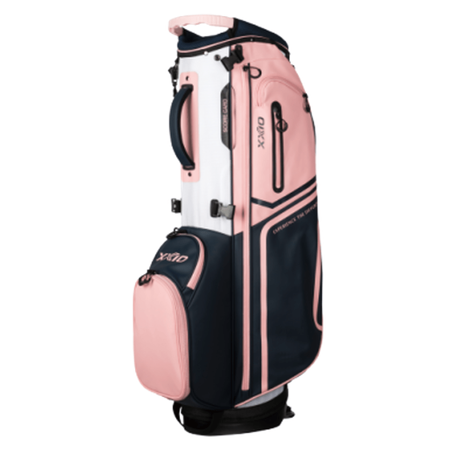 The XXIO Ladies Stand Bag features a pink, white, and navy design, multiple zippered pockets for storage, a top handle, and a side handle for easy carrying or push cart use.