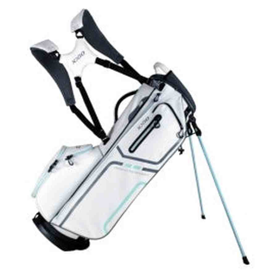 The XXIO Ladies Stand Bag is white with teal accents, features multiple zippered pockets, dual padded shoulder straps, and two extended legs for stability.