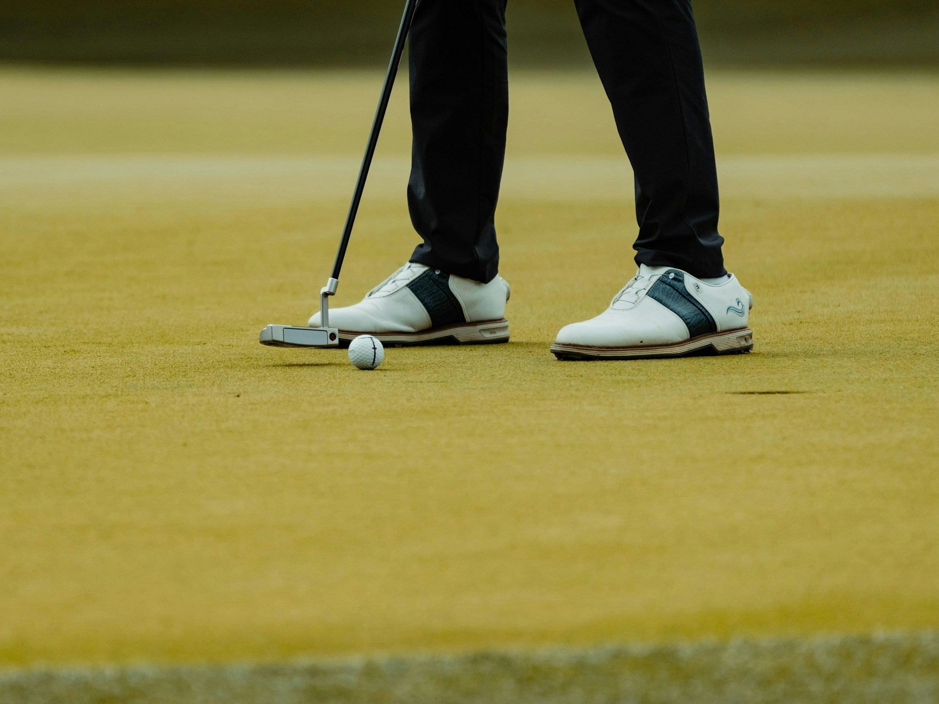 detail of the under armour golf pants weared by a golfer that is about to put a ball