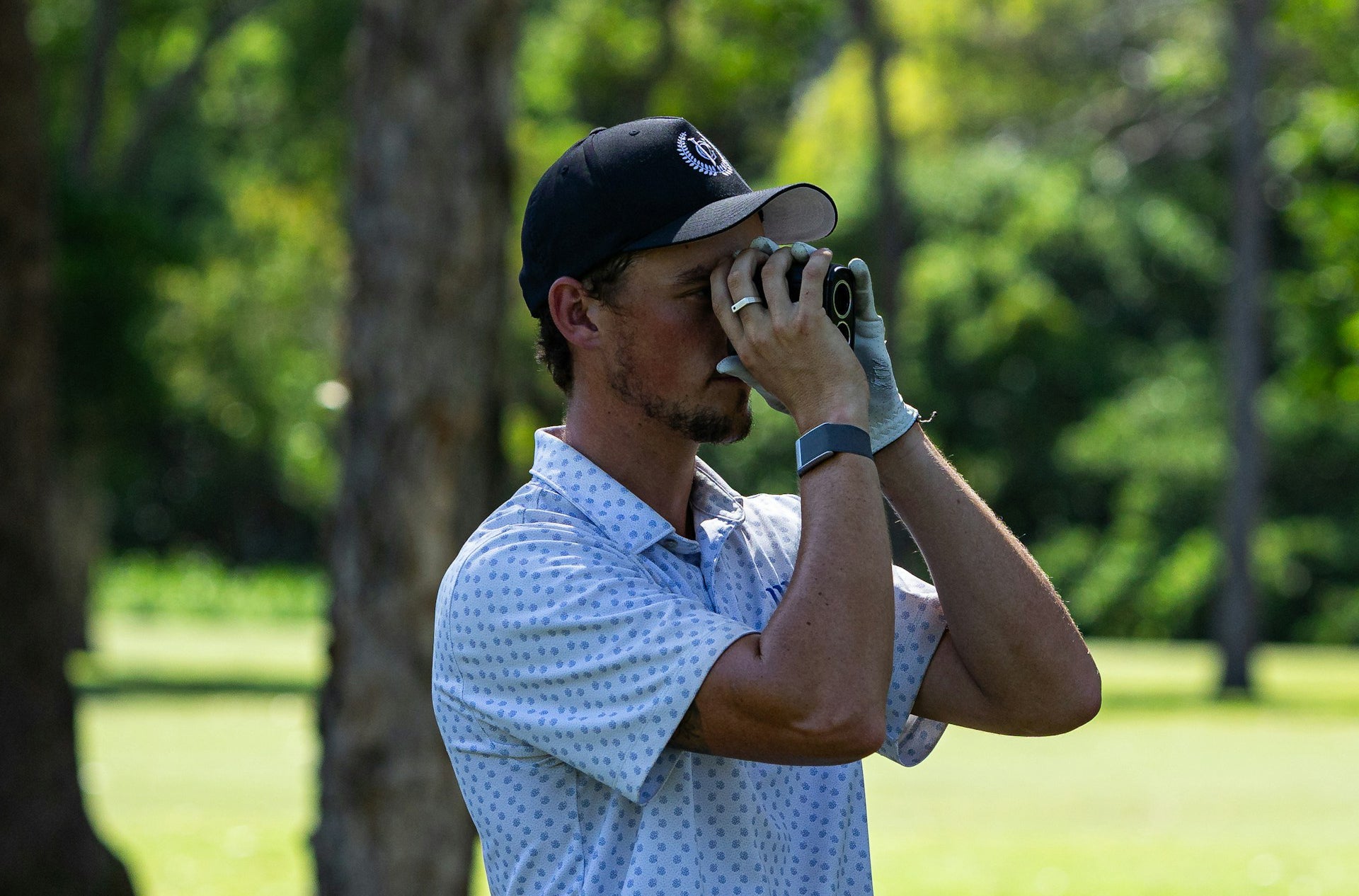 golf player wearing a golf watch while uses a rangefinder