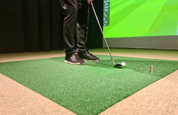 view of an indoor golf simulator where a golf player is getting ready to hit the ball