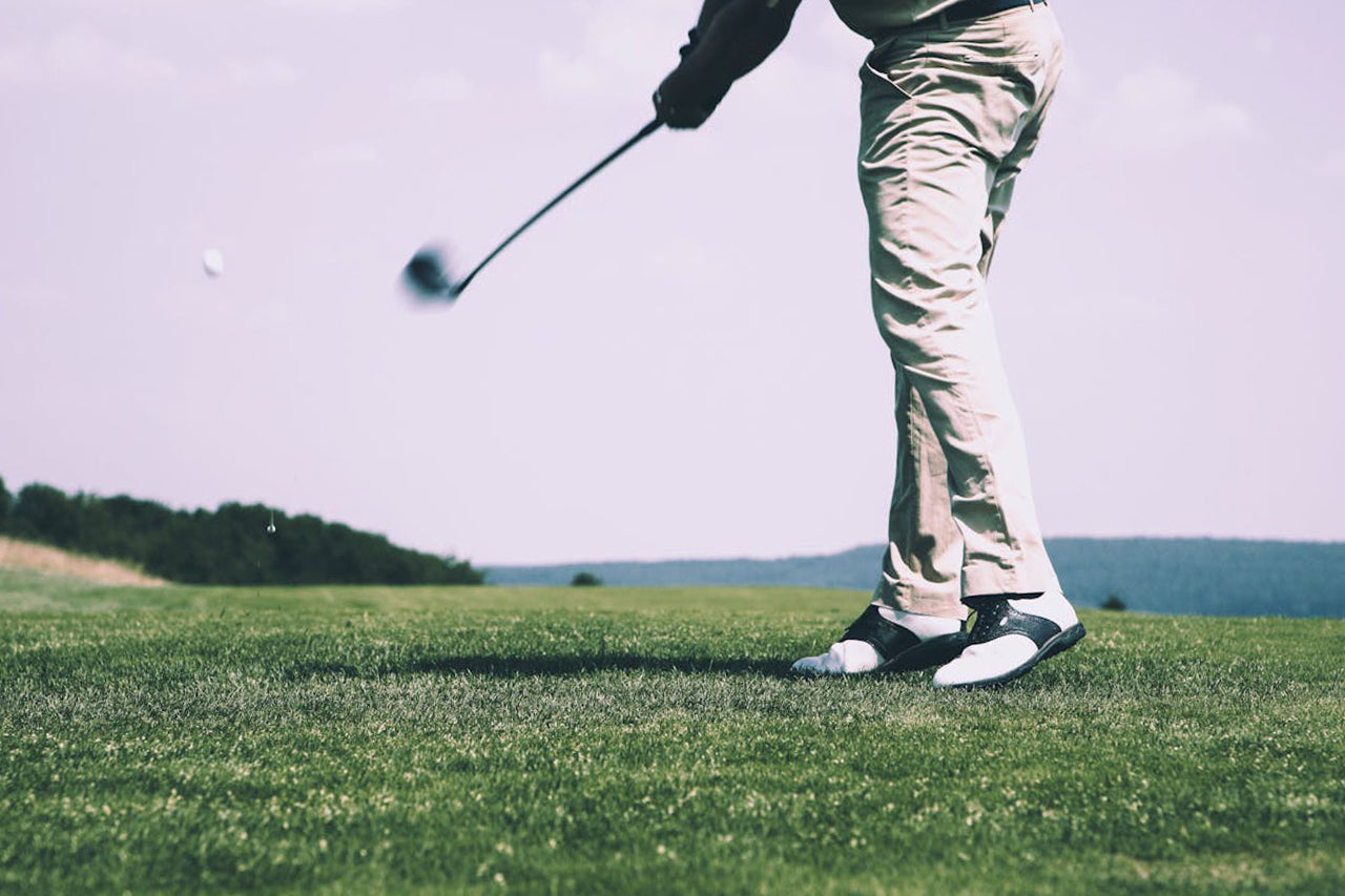 left handed golf player hitting a ball with a left handed golf club