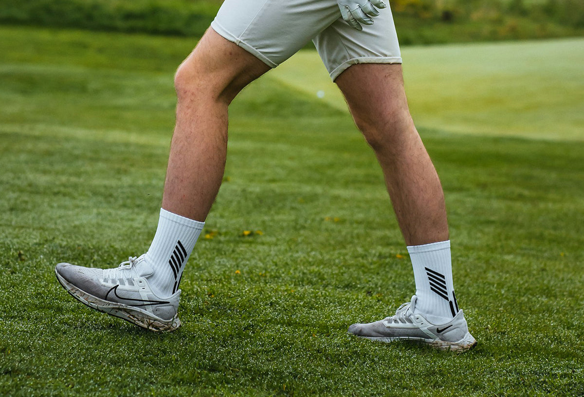 detail of a golf player walking on the field wearing spikeless golf shoes