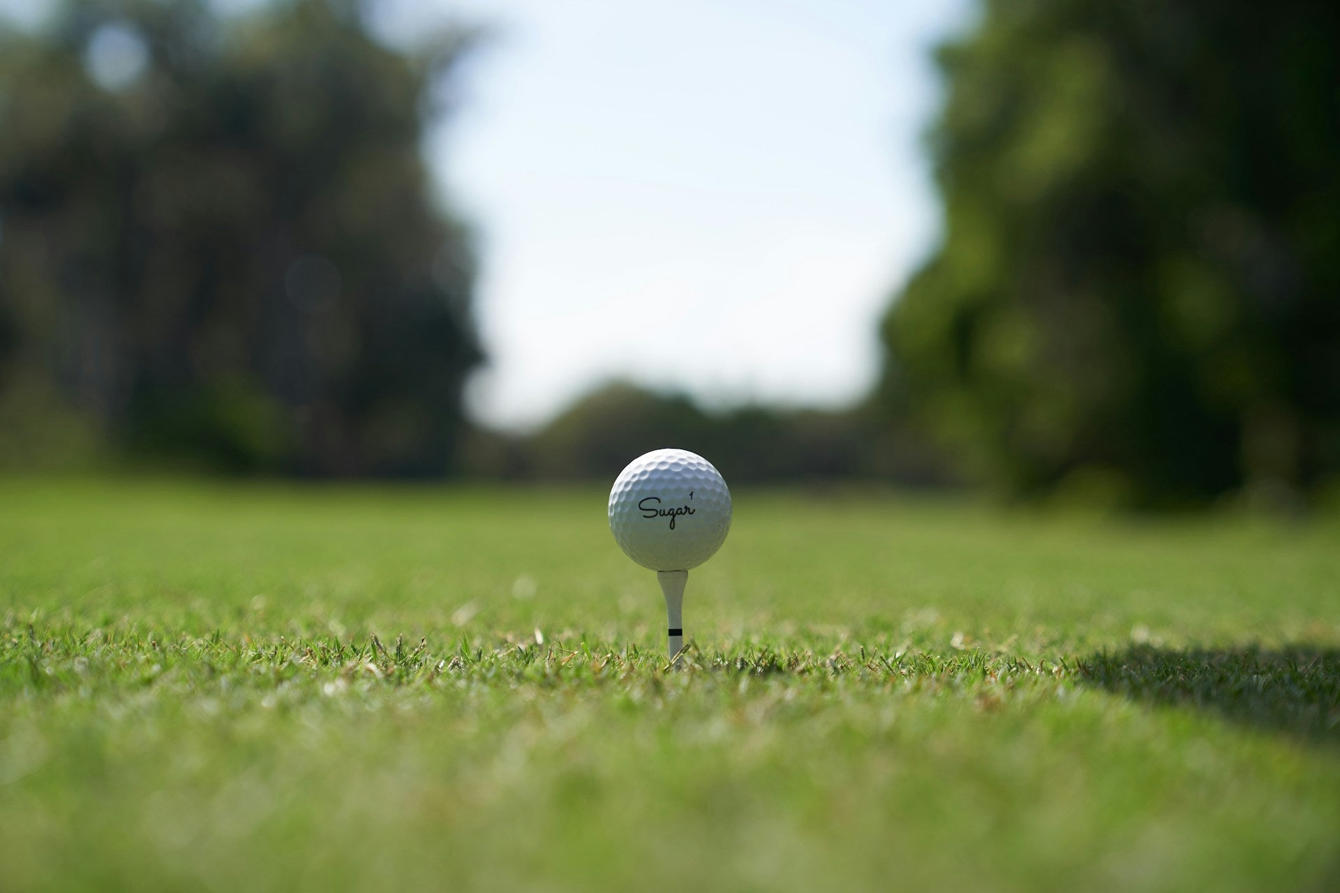 golf ball over tee in view close to the ground in a green golf field
