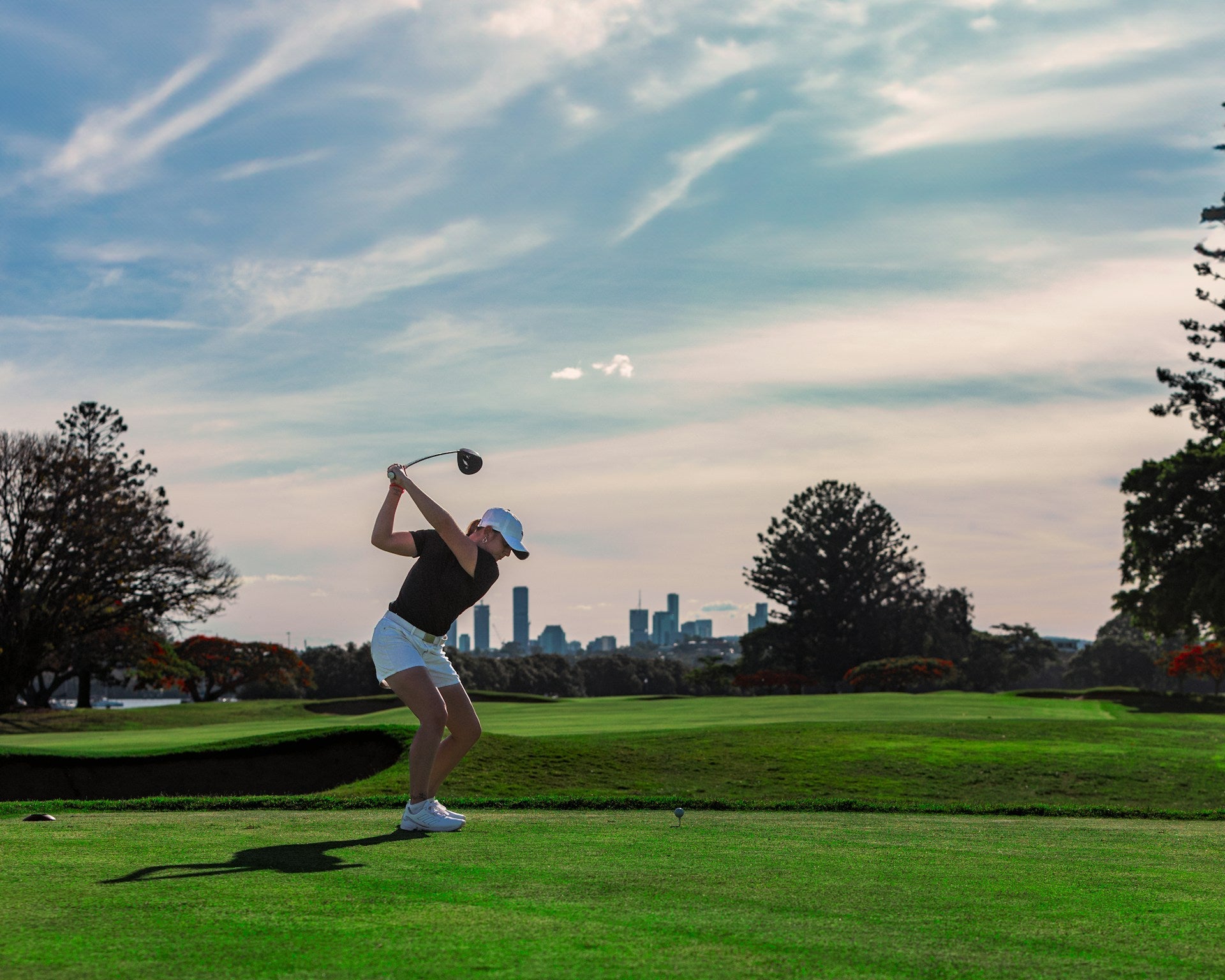 female golfer wearing women's golf apparel in the field while playing