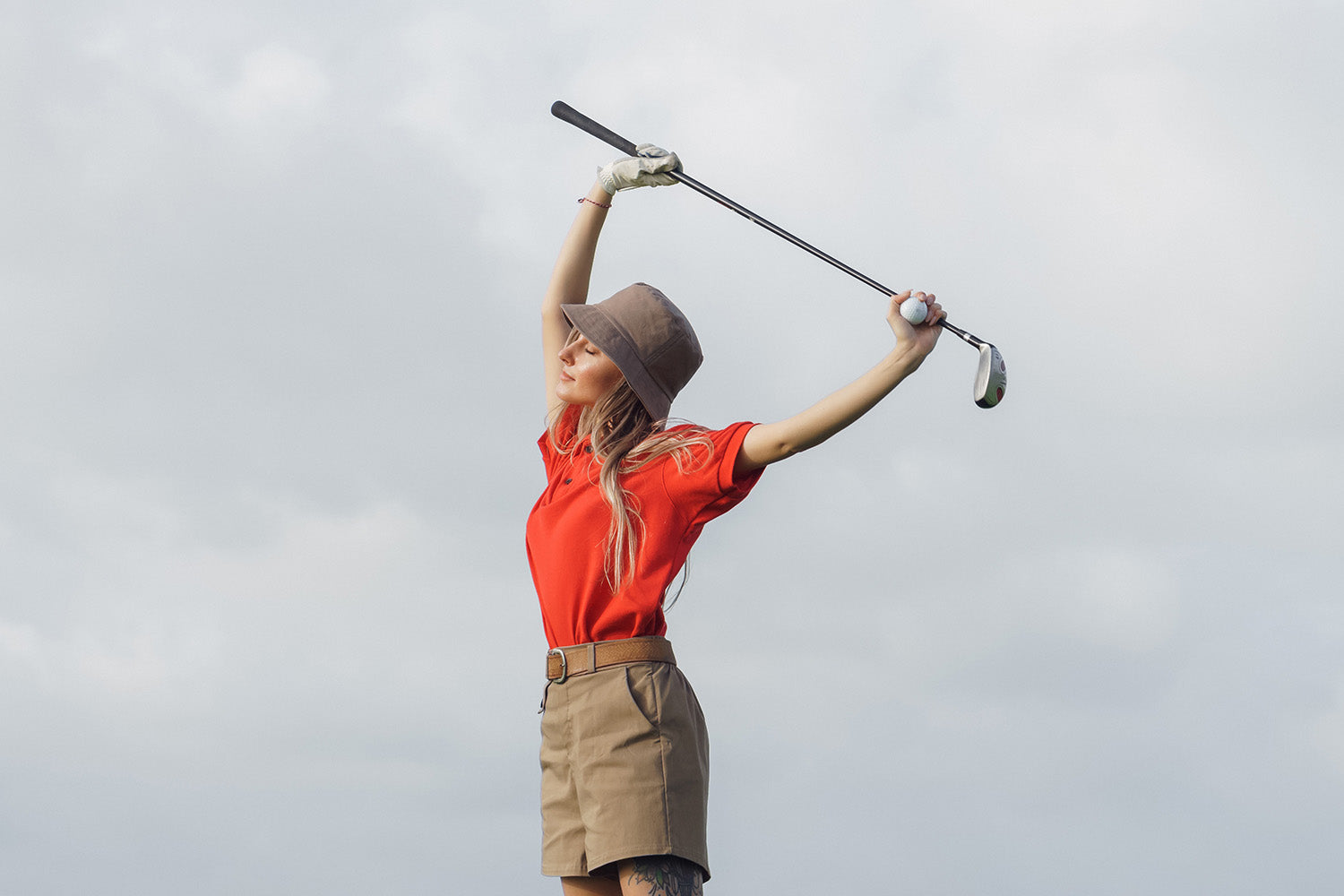 women golf player wearing trendy golf attire in 2023 stretching with a club