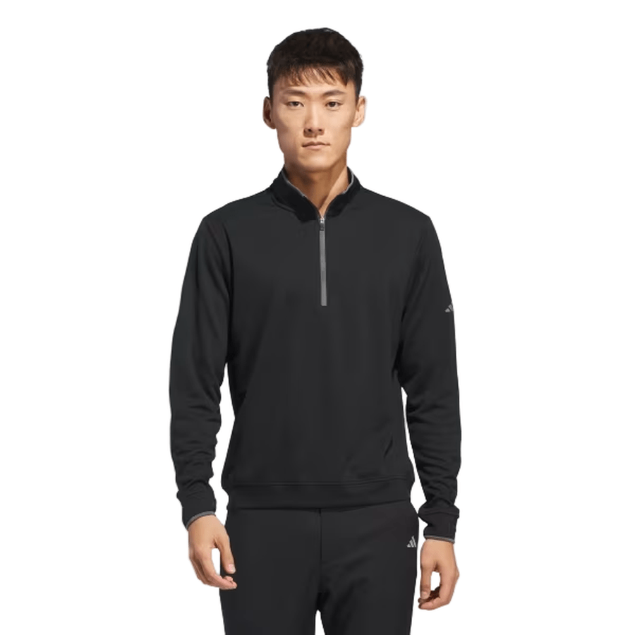 A young man faces forward, wearing the Adidas Lightweight Half-Zip Top—final sale—in black with matching pants made from recycled materials. The background is plain white.