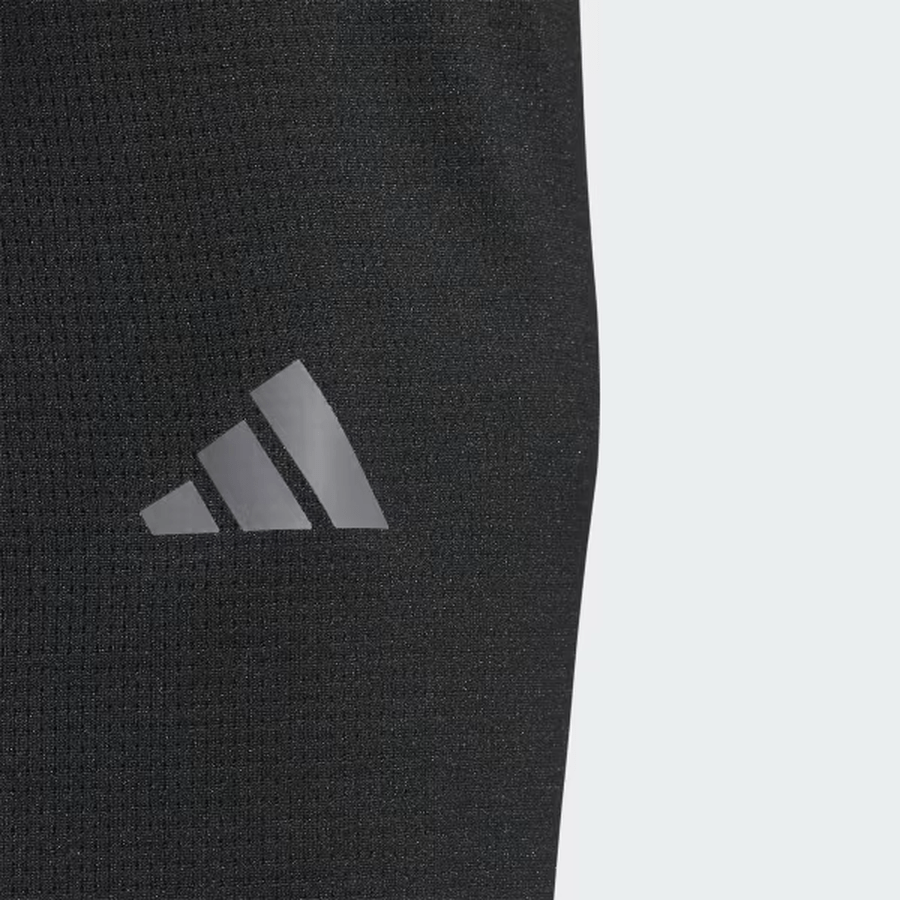 Close-up of black recycled fabric on the Adidas Lightweight Half-Zip Top - Final Sale, featuring a light gray adidas logo with three diagonal stripes and a triangle near the bottom left.