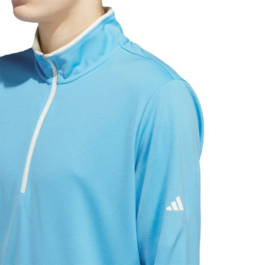 A person wears the Adidas Lightweight Half-Zip Top in light blue with a white quarter-zip and small Adidas logo on the left sleeve, made from recycled materials. Only the upper body and part of the face are visible.