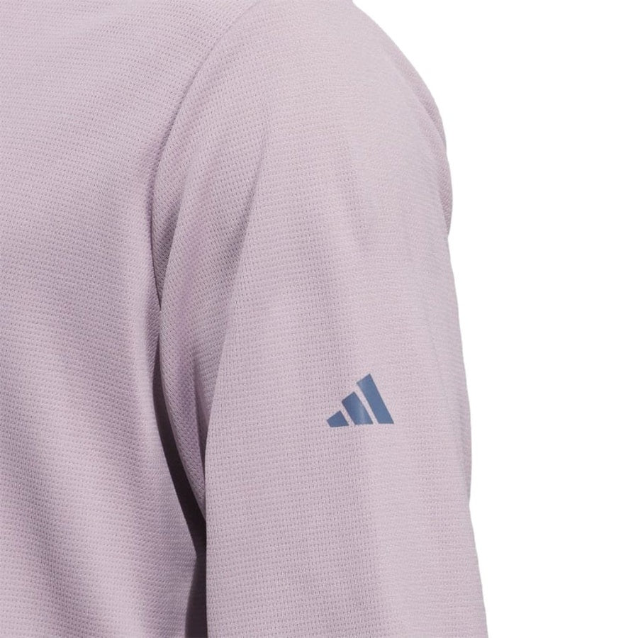 Close-up of a person wearing the Adidas Lightweight Half-Zip Top in light purple with a dark blue adidas logo on the left sleeve. Made with recycled materials. Set against a white background. Final Sale.