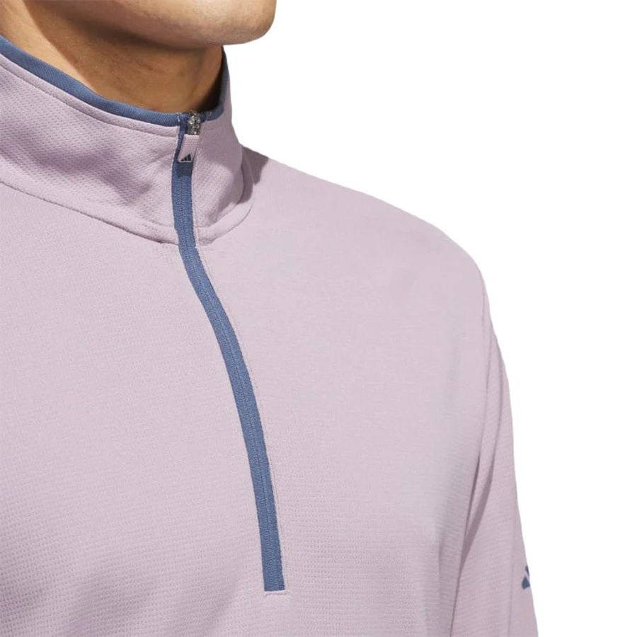 A close-up shows a person in the Adidas Lightweight Half-Zip Top—light purple with a blue zipper and collar trim, made from recycled materials. Only the lower face, neck, and chest are visible against a white background.