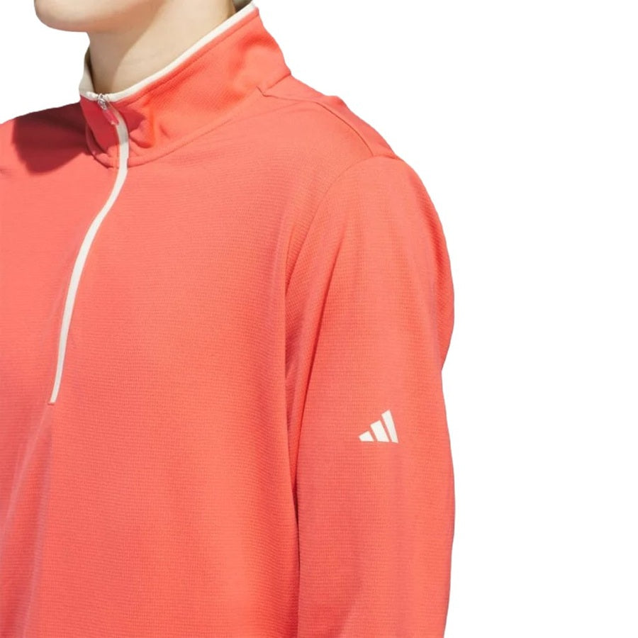 Model wears the Adidas Lightweight Half-Zip Top in coral, featuring a white zipper and sleeve logo. Shown from shoulders up against a white background. This eco-friendly pullover is made with recycled materials. Final Sale.