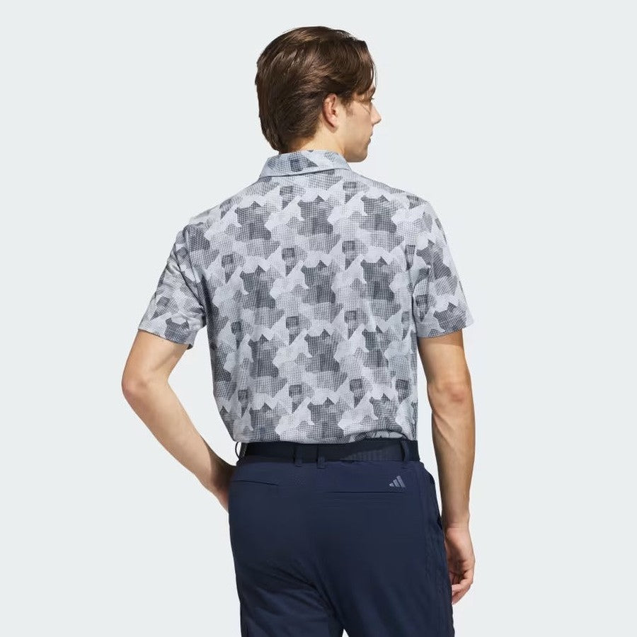 A man faces away, wearing a short-sleeve, gray and white geometric adidas 2025 Go-To Printed Polo Shirt made from recycled materials with dark blue pants, set against a light background.